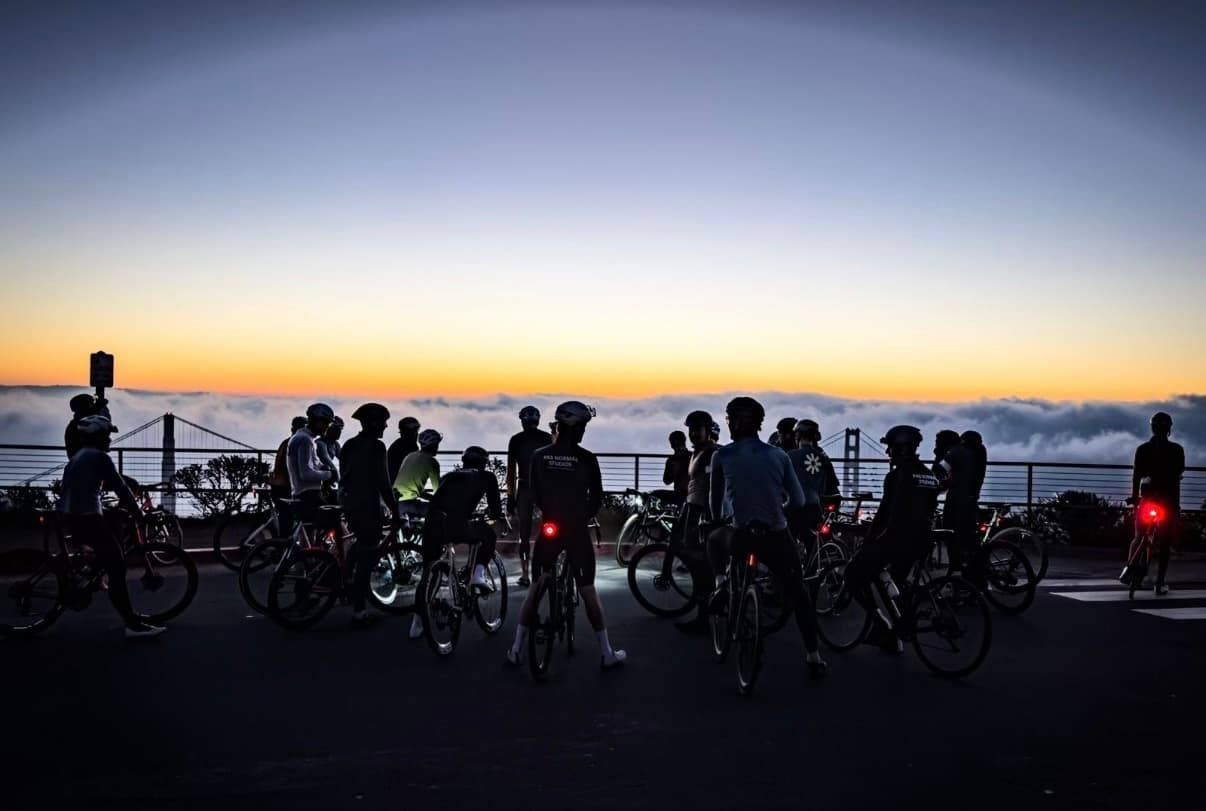 Cyclists gathered above the clouds near the Golden Gate at dawn